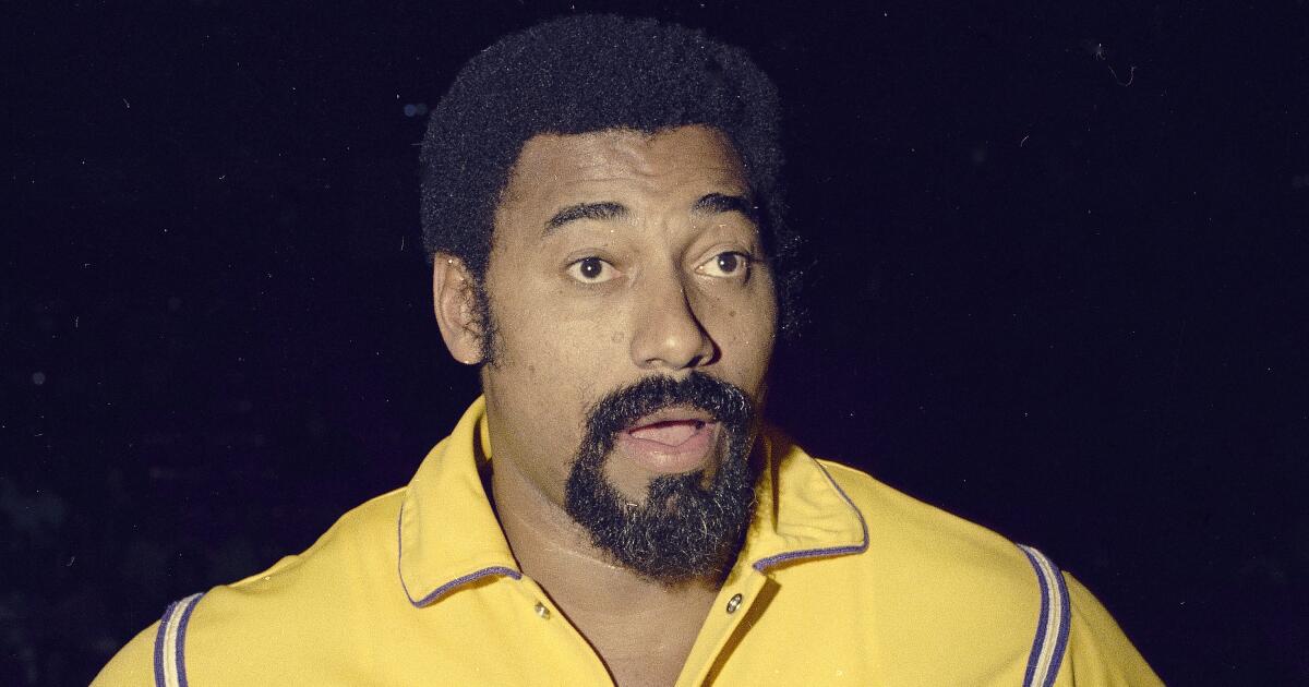 Wilt Chamberlain stands with his mouth open while wearing a yellow Lakers warmup jacket